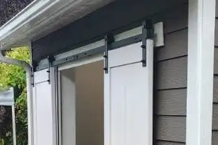 Small lean-to shed with white barn-style doors, lap siding, white trim and a new gutter, Clinton