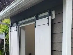 Small lean-to shed with white barn-style doors, lap siding, white trim and a new gutter, Clinton
